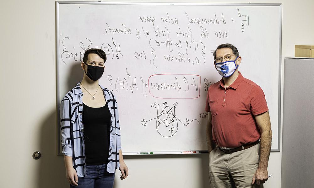 教授和学生站在黑板前写着方程式.